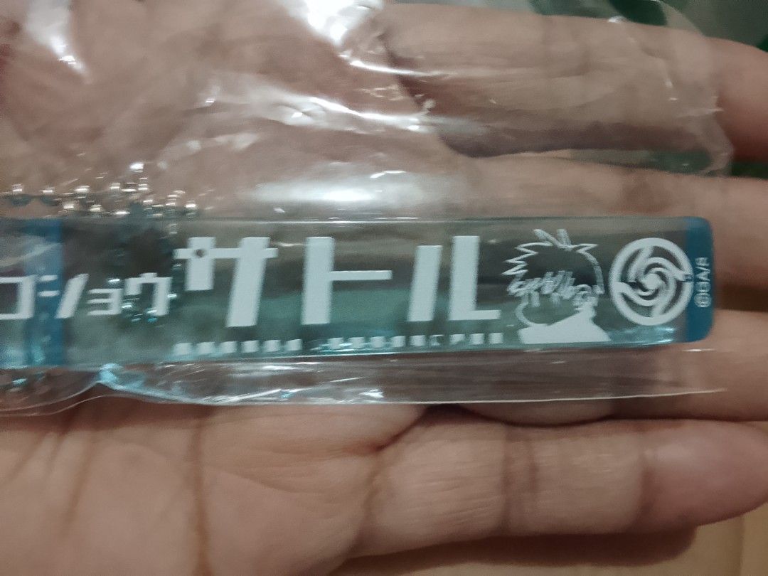 Gojo Satoru Keychain (Category: J-Wave Merchandise) located in Santa Rosa. Submitted by animemerchcollection (Listing ID 1427958001, Image 2). Description: Keychain features Gojo Satoru from Jujutsu Kaisen. It has a blue and white design with Japanese text and an illustration of Gojo Satoru. The keychain includes a ball chain for easy attachment to bags or keys. It is a collectible item for fans of the anime series..