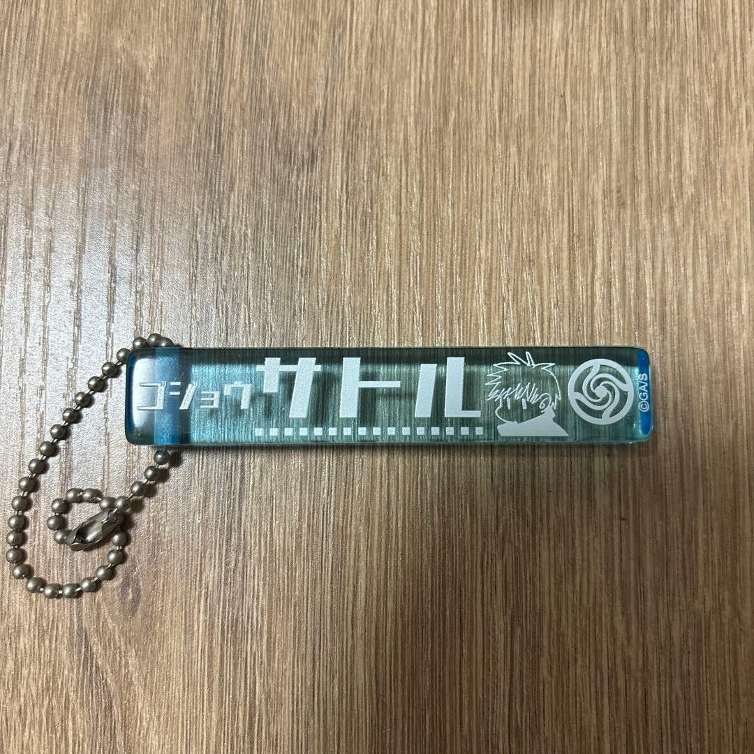 Gojo Satoru Keychain (Category: J-Wave Merchandise) located in Santa Rosa. Submitted by animemerchcollection (Listing ID 1427958001, Image 1). Description: Keychain features Gojo Satoru from Jujutsu Kaisen. It has a blue and white design with Japanese text and an illustration of Gojo Satoru. The keychain includes a ball chain for easy attachment to bags or keys. It is a collectible item for fans of the anime series..