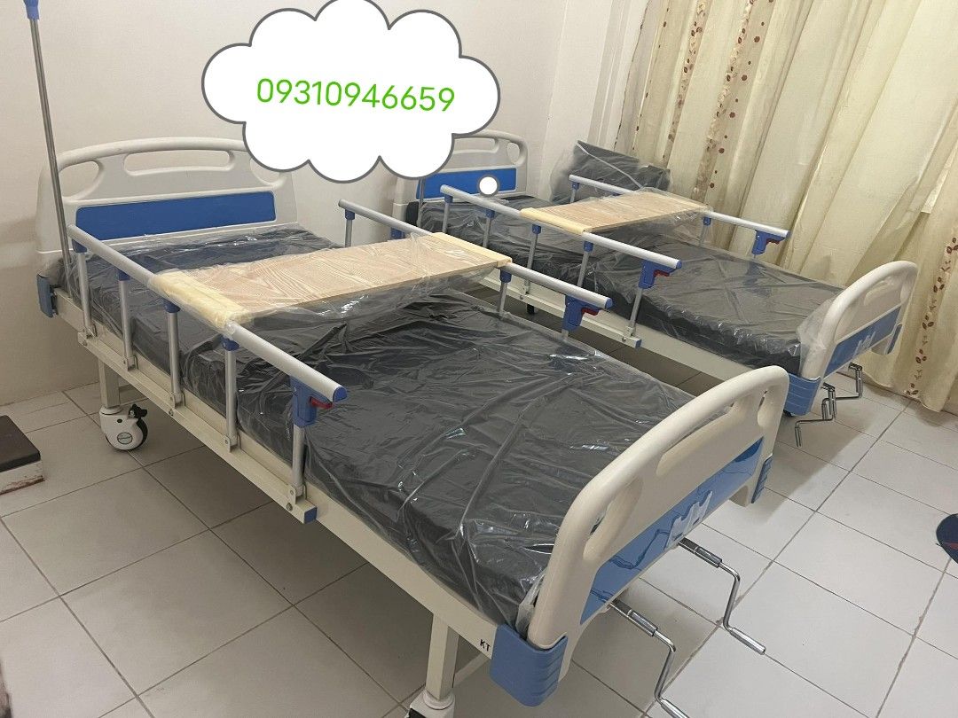 Hospital Bed with Side Rails (Category: Medical Supplies & Tools) located in Manila. Submitted by rheatapdas75609 (Listing ID 1427983399, Image 2). Description: Hospital bed with side rails and a wooden tray. Features a blue mattress and wheels for easy movement. The bed frame is white with blue accents. Includes a crank mechanism for adjusting the bed's position. Contact 09310946659 for inquiries..