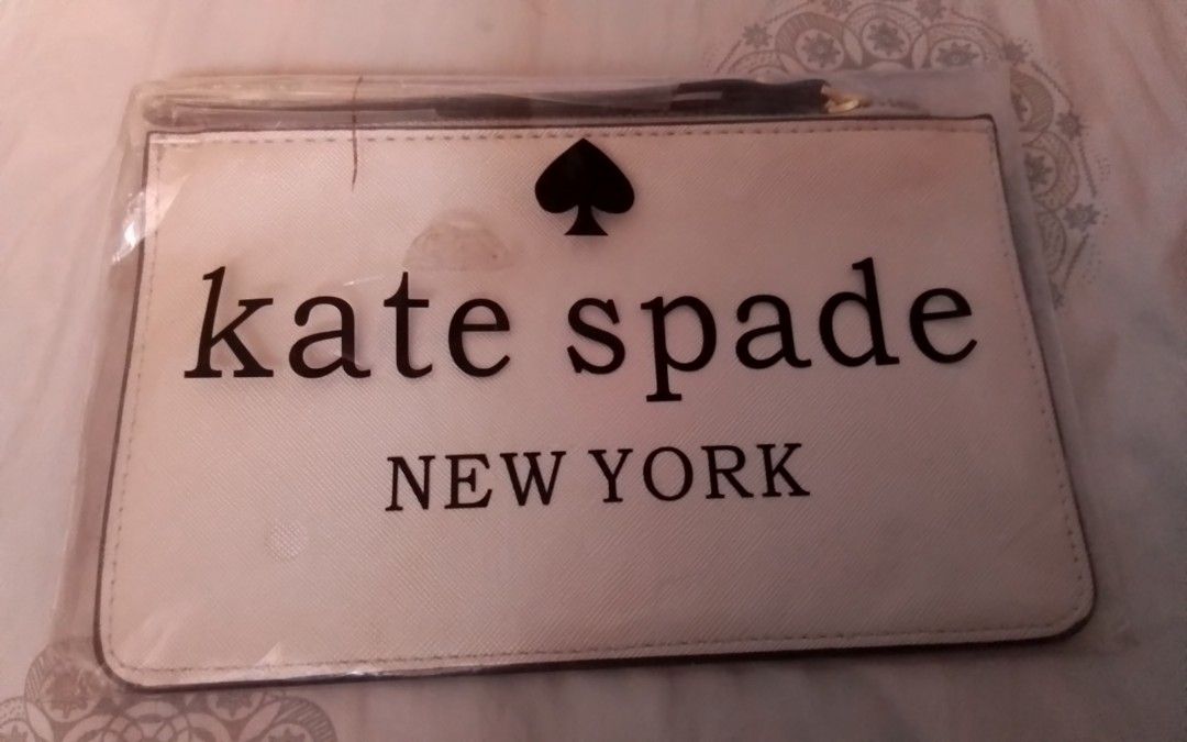 Kate Spade New York Clutch (Category: Clutches) located in Manila. Submitted by sakinto (Listing ID 1428009235, Image 2). Description: Kate Spade New York clutch. Features a wrist strap and a zip closure. The exterior is white with the Kate Spade logo in gold. The back of the clutch has the Kate Spade logo in black. Includes original packaging..