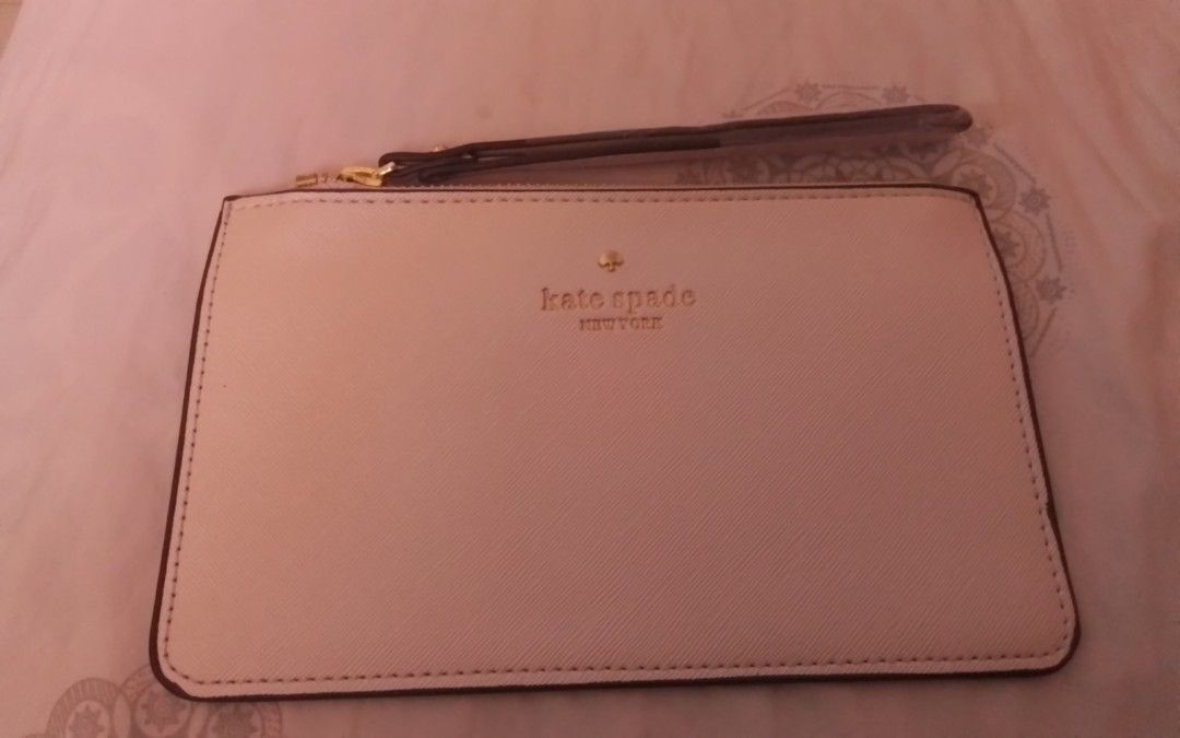 Kate Spade New York Clutch (Category: Clutches) located in Manila. Submitted by sakinto (Listing ID 1428009235, Image 1). Description: Kate Spade New York clutch. Features a wrist strap and a zip closure. The exterior is white with the Kate Spade logo in gold. The back of the clutch has the Kate Spade logo in black. Includes original packaging..