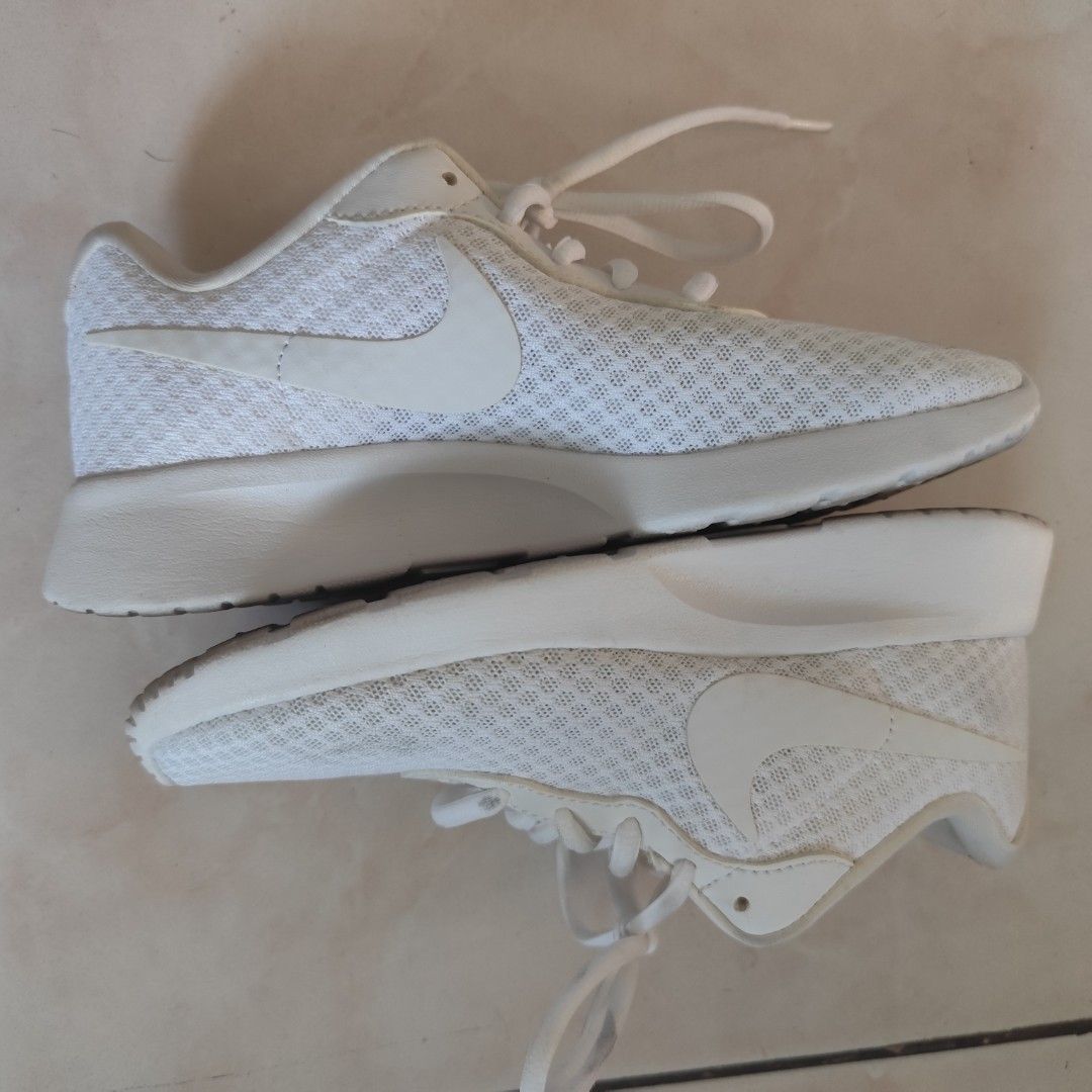 Nike Tanjun White Sneakers (Category: Sneakers) located in Bulacan. Submitted by gentlestorm_408dc4 (Listing ID 1427945541, Image 2). Description: White Nike Tanju sneakers. Features a mesh upper and a white sole. The Nike swoosh logo is visible on the side. The insole is green with a Nike logo. The laces are white. Original from US 9 inches long, size 5 My aunt gave it to me Im size 6 but I am now size 7 after giving birth.