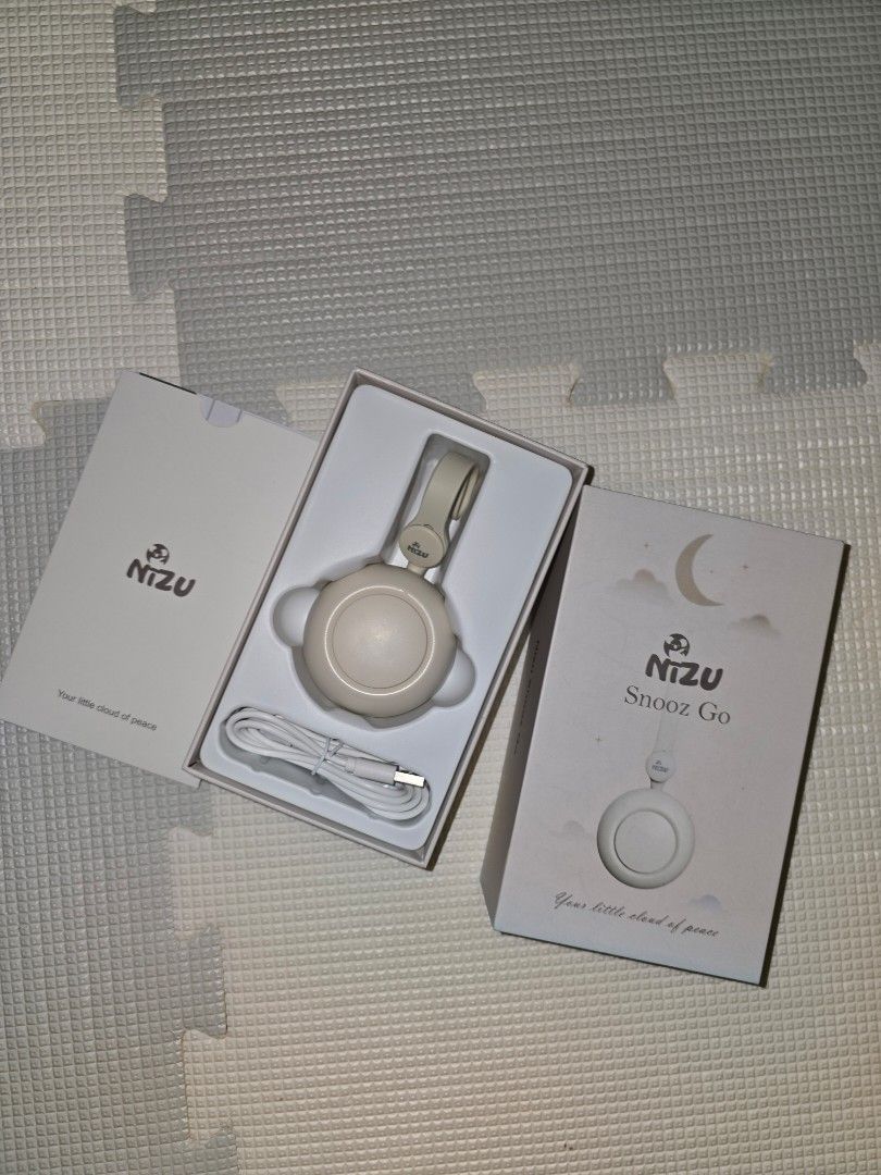 NIZU Snooz Go Portable Sound Machine (Category: Soundbars, Speakers & Amplifiers) located in Pasig City. Submitted by momofwillow (Listing ID 1428058994, Image 1). Description: NIZU Snooz Go is a portable sound machine designed to help babies sleep. It comes with a USB charging cable and can be clipped onto strollers, baby carriers, or diaper bags. The device has multiple buttons and a light ring. The packaging includes the device, a charging cab