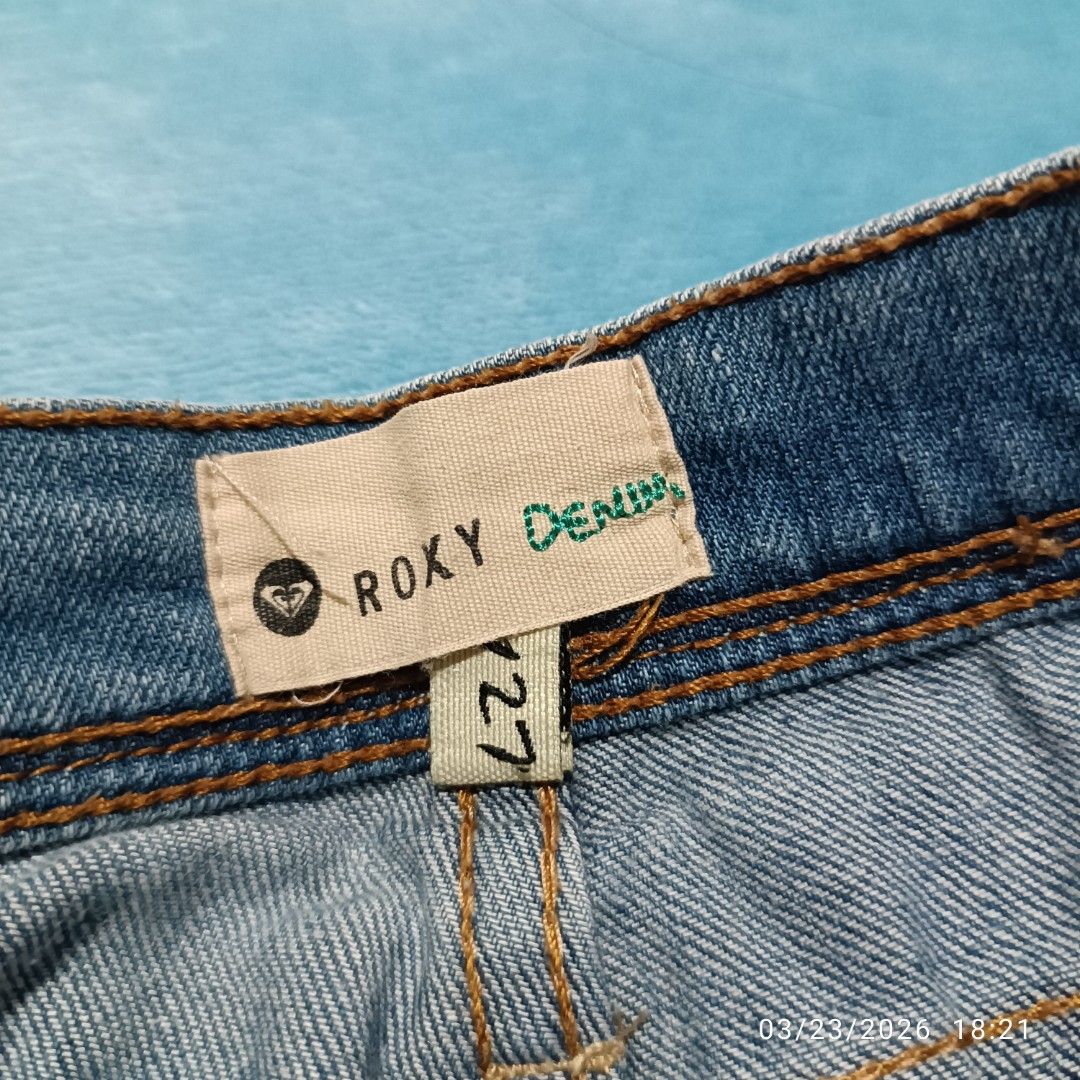 Roxy Denim Embroidered Shorts - Size 27 (Category: Shorts) located in Bacoor. Submitted by pamelott (Listing ID 1428022618, Image 3). Description: ​Brand: Roxy Denim (as seen on the inner waist tag and branded button). ​Style: Low-rise denim cut-offs with a heavily frayed/distressed hem. ​Size: The tag indicates a size 27. ​Color: Light-wash blue denim with traditional contrast copper stitching..