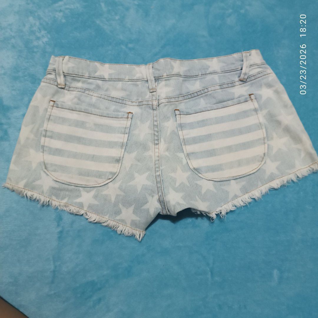 Roxy Denim Shorts Size 27 (Category: Shorts) located in Bacoor. Submitted by pamelott (Listing ID 1428022142, Image 3). Description: ​Brand: Roxy Denim ​Size: S / 27 (Small, Waist size 27) ​Style: Low-to-mid rise cut-off denim shorts. ​Design & Pattern: * Americana Theme: Features a unique mix of white stars and vertical stripes over a light blue denim wash. ​Front Pockets: Large, rounded "patch-style" front pockets with a striped pattern that co