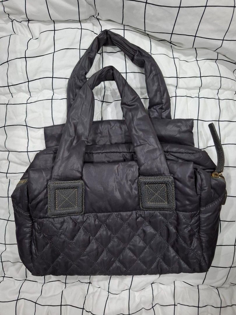 Chanel Quilted Tote Bag (Category: Luxury Bags & Wallets) located in Mandaue City. Submitted by mariah_preloved (Listing ID 1428097697, Image 2). Description: Quilted tote bag with a Chanel logo on the front. It features two handles and a zipper closure. The interior has a zippered pocket. The bag is a dark color, possibly black or a very dark grey. The stitching pattern is a diamond quilt..