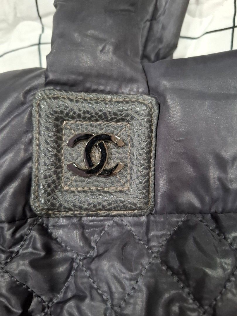 Chanel Quilted Tote Bag (Category: Luxury Bags & Wallets) located in Mandaue City. Submitted by mariah_preloved (Listing ID 1428097697, Image 3). Description: Quilted tote bag with a Chanel logo on the front. It features two handles and a zipper closure. The interior has a zippered pocket. The bag is a dark color, possibly black or a very dark grey. The stitching pattern is a diamond quilt..