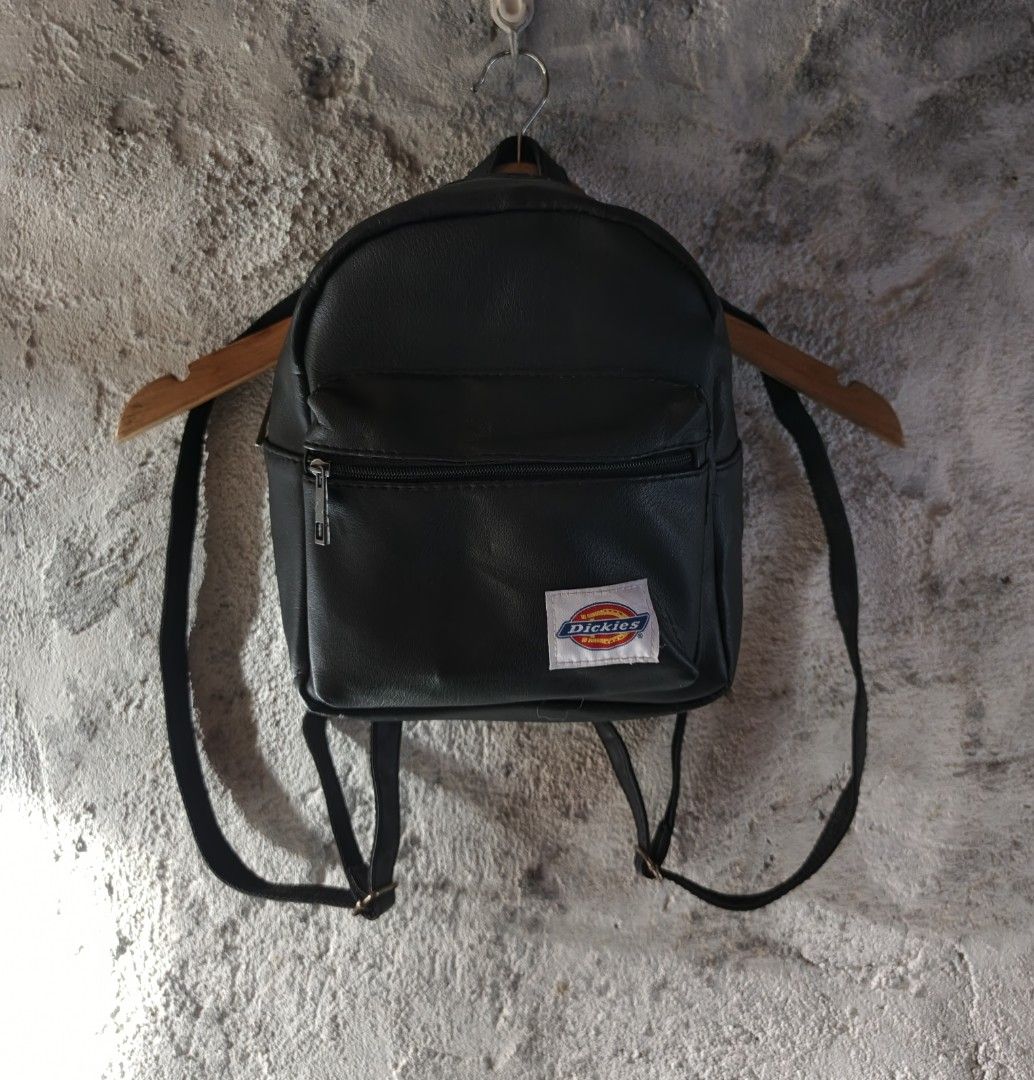 DICKIES | Men's Mini Backpack Black (Category: Backpacks) located in Naga. Submitted by bossyingthrifts (Listing ID 1428202240, Image 1). Description: DICKIES | Men's Mini Backpack Black Mini backpack features a black exterior with a front zippered pocket. It has adjustable shoulder straps and a top handle for carrying. The Dickies logo is prominently displayed on the front. Color rate: 9.5/10 Excellent Condition Issue: minimal rusty buckles, not