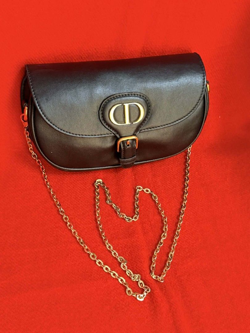 Dior Black Shoulder Bag with Gold Chain (Category: Luxury Bags & Wallets) located in Quezon City. Submitted by rolenalma (Listing ID 1428206802, Image 1). Description: Dior Bobby East - West bag. Elegant black shoulder bag featuring a gold chain strap and a gold-tone CD logo on the front. The bag has a flap closure with a buckle. The back of the bag has a subtle embossed pattern. A small pocket is visible on the back..