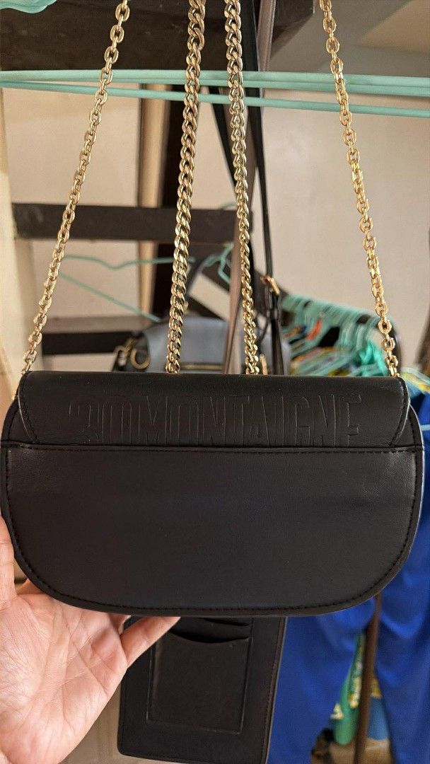 Dior Black Shoulder Bag with Gold Chain (Category: Luxury Bags & Wallets) located in Quezon City. Submitted by rolenalma (Listing ID 1428206802, Image 2). Description: Dior Bobby East - West bag. Elegant black shoulder bag featuring a gold chain strap and a gold-tone CD logo on the front. The bag has a flap closure with a buckle. The back of the bag has a subtle embossed pattern. A small pocket is visible on the back..