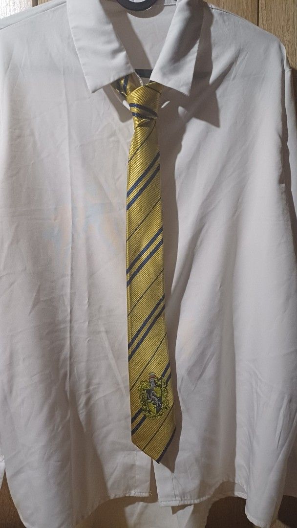 Hogwarts Hufflepuff Tie (Category: Ties) located in Caloocan City. Submitted by preloved.decluttering (Listing ID 1428211142, Image 2). Description: Tie features the Hufflepuff house crest and colors. It has a yellow background with navy blue stripes. The tie is made of a textured material. It is suitable for cosplay or adding a touch of Hogwarts to your everyday wear. Only used once, no damage. (Button down shirt NOT included.).