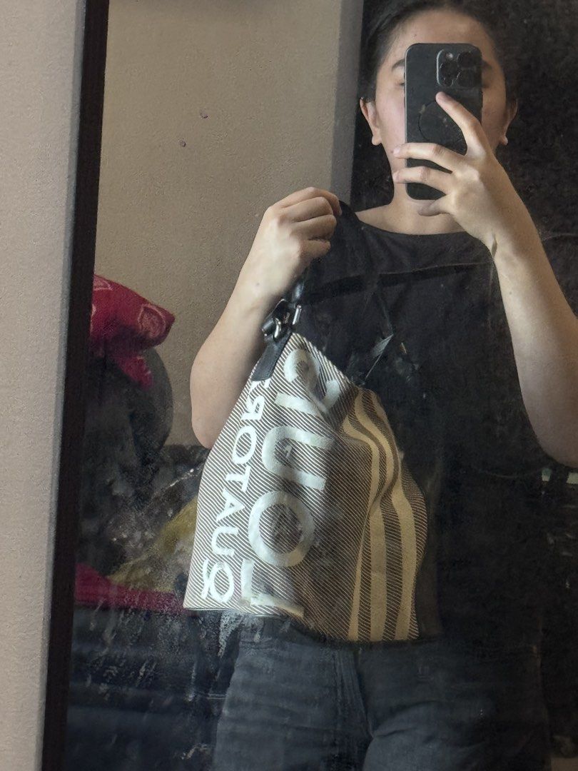 Louis Quatorze Bucket Bag (Category: Luxury Bags & Wallets) located in Manila. Submitted by thriftyhaven2023 (Listing ID 1428105058, Image 3). Description: Bucket bag features a striped canvas design with the brand name printed on the side. It has a black leather base, handle, and strap. The interior is lined with a dark blue fabric and includes a small pouch. The bag can be worn over the shoulder or carried by the handle. 9/10 condition No flaws