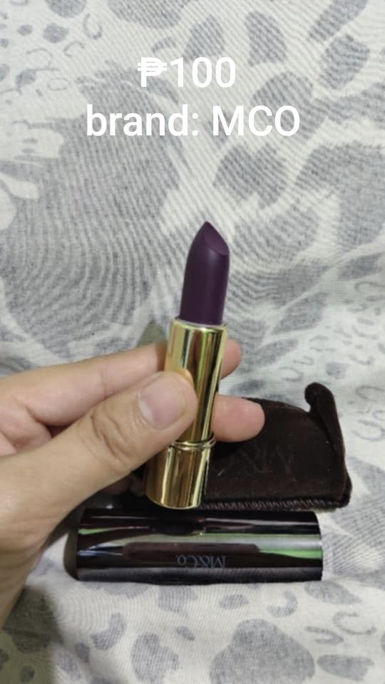 MCO Lipstick (Category: Makeup) located in Manila. Submitted by shairinelurvs (Listing ID 1428202487, Image 1). Description: MCO lipstick in a dark purple shade. The lipstick has a gold tube and comes with a small pouch. The price is P100..