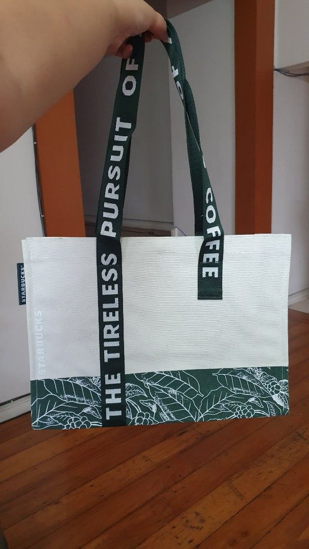 Starbucks Tote Bag (Category: Tote Bags) located in San Juan City. Submitted by leyuri_shop2025 (Listing ID 1428200822, Image 1). Description: From Starbucks China Exclusives Dragon Boat Festival 2025 Series. Stylish Canvas tote bag with coating inside. Features a white body with a green leaf pattern at the bottom and Starbucks branding on the strap. Includes an internal pocket. Spacious enough to carry various items, as shown in the images. Perf