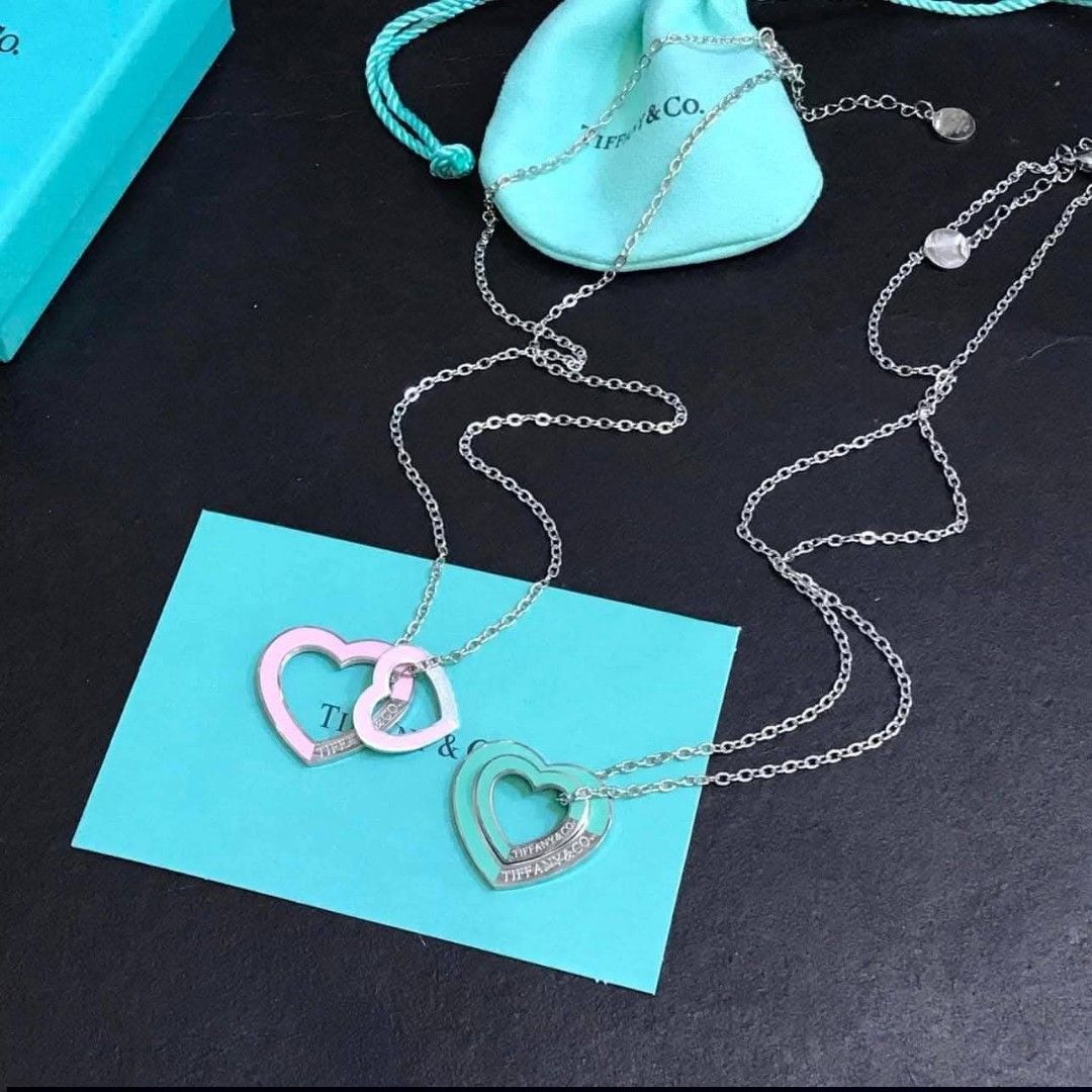 Tiffany & Co. Double Heart Necklace (Category: Luxury Accessories) located in Manila. Submitted by celstainlessjewelry (Listing ID 1428185928, Image 1). Description: Tiffany & Co. necklace features a double heart pendant design. The necklace comes with a box, a pouch, and a card. The hearts are available in various colors, including pink and turquoise, with the Tiffany & Co. logo visible on the pendant..