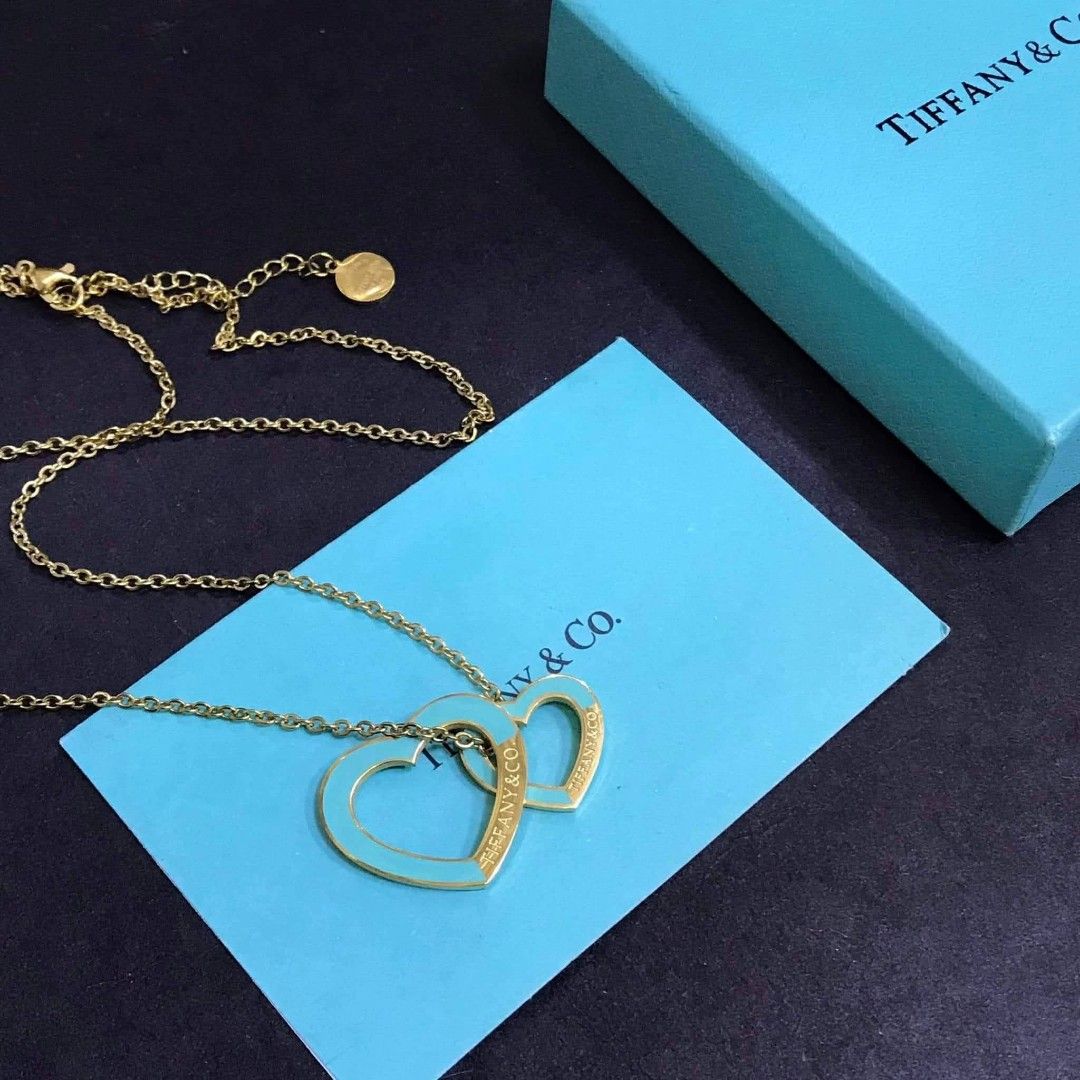 Tiffany & Co. Double Heart Necklace (Category: Luxury Accessories) located in Manila. Submitted by celstainlessjewelry (Listing ID 1428185928, Image 2). Description: Tiffany & Co. necklace features a double heart pendant design. The necklace comes with a box, a pouch, and a card. The hearts are available in various colors, including pink and turquoise, with the Tiffany & Co. logo visible on the pendant..