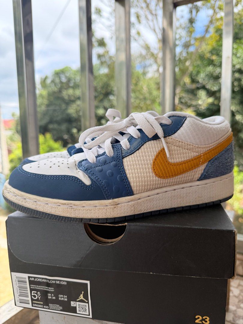 ORIGINAL Air Jordan 1 Low SE (GS) (Category: Sneakers) located in Silang. Submitted by abcdenz (Listing ID 1428299461, Image 1). Description: Air Jordan 1 Low SE (GS) in French Blue/Chutney/White colorway. Features a mix of materials and textures, including leather and textile panels. The shoes have a white base with blue and yellow accents. Comes with the original box. Size is 5.5Y..