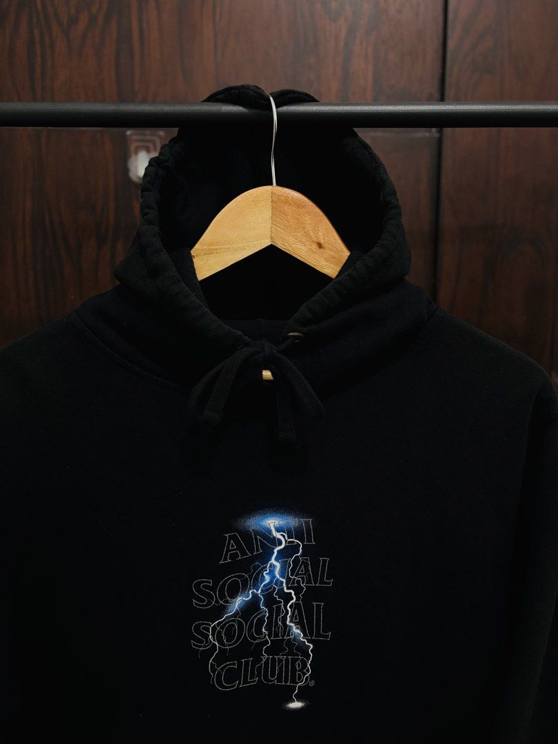 Anti Social Social Club Lightning Hoodie (Category: Hoodies) located in Binan City. Submitted by worldofthrift1001 (Listing ID 1428405166, Image 3). Description: Black hoodie featuring the Anti Social Social Club logo with a lightning bolt design on the front and back. It has a hood with drawstrings and a kangaroo pocket. The hoodie is displayed on a hanger..