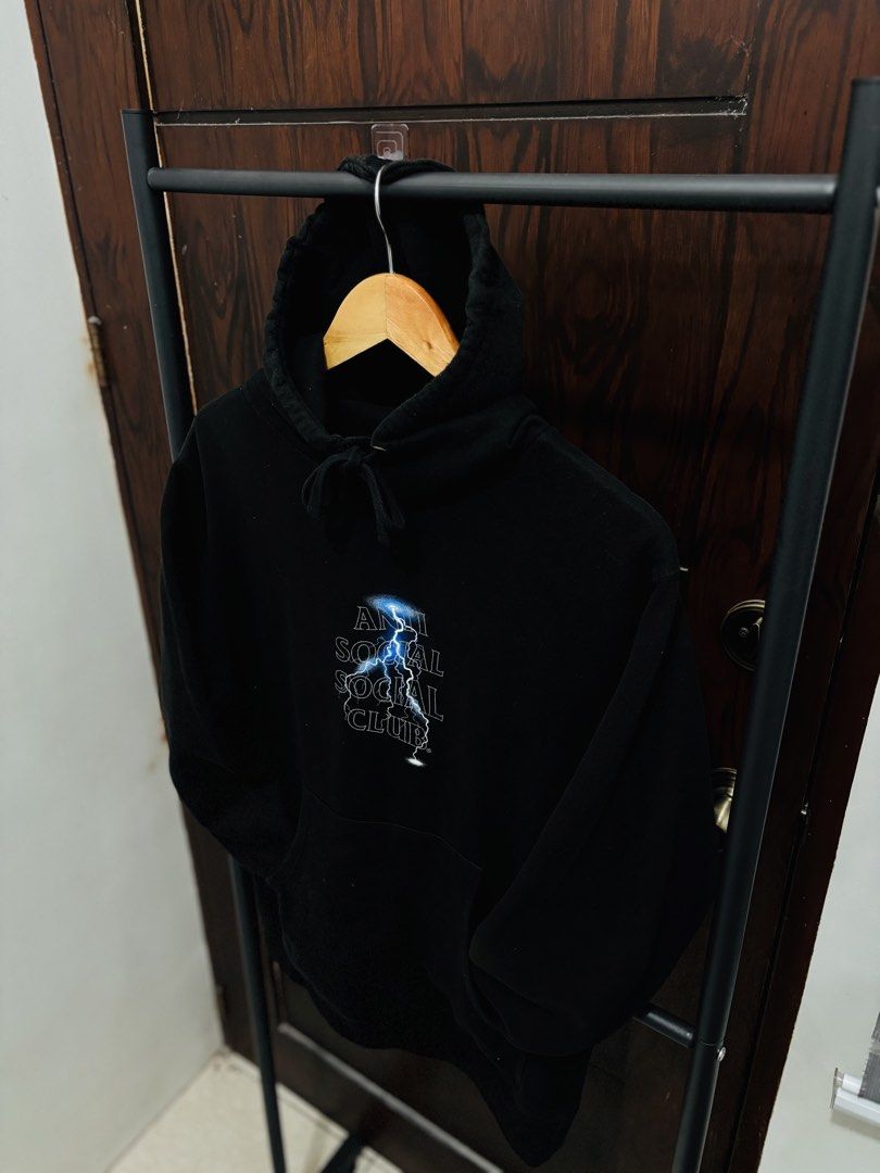 Anti Social Social Club Lightning Hoodie (Category: Hoodies) located in Binan City. Submitted by worldofthrift1001 (Listing ID 1428405166, Image 2). Description: Black hoodie featuring the Anti Social Social Club logo with a lightning bolt design on the front and back. It has a hood with drawstrings and a kangaroo pocket. The hoodie is displayed on a hanger..