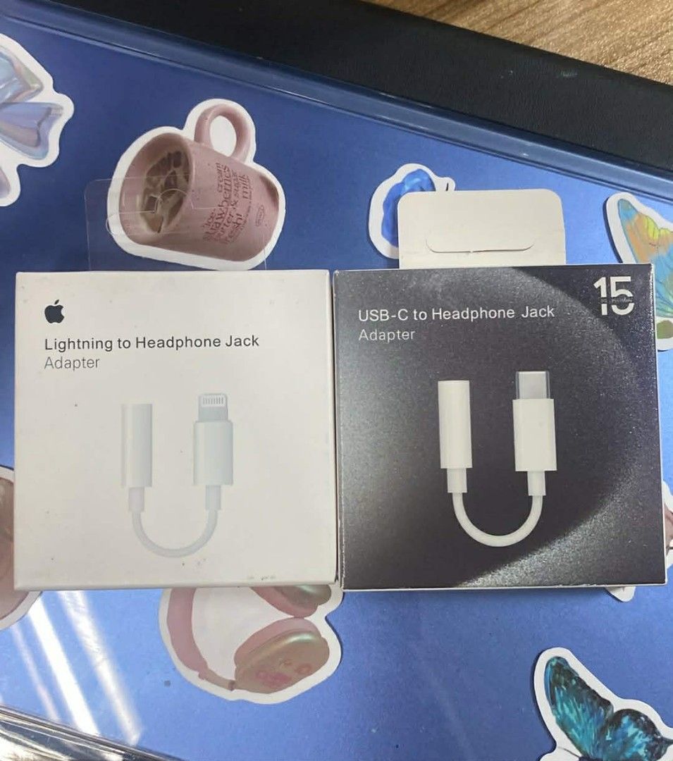 Apple Lightning to Headphone Jack Adapter & USB-C Adapter (Category: Chargers & Cables) located in Manila. Submitted by milasgadgetph (Listing ID 1428260570, Image 1). Description: Two Apple adapters are available: a Lightning to Headphone Jack Adapter and a USB-C to Headphone Jack Adapter. Both are in their original packaging. The Lightning adapter is in a white box, while the USB-C adapter is in a black box. Both adapters are white..