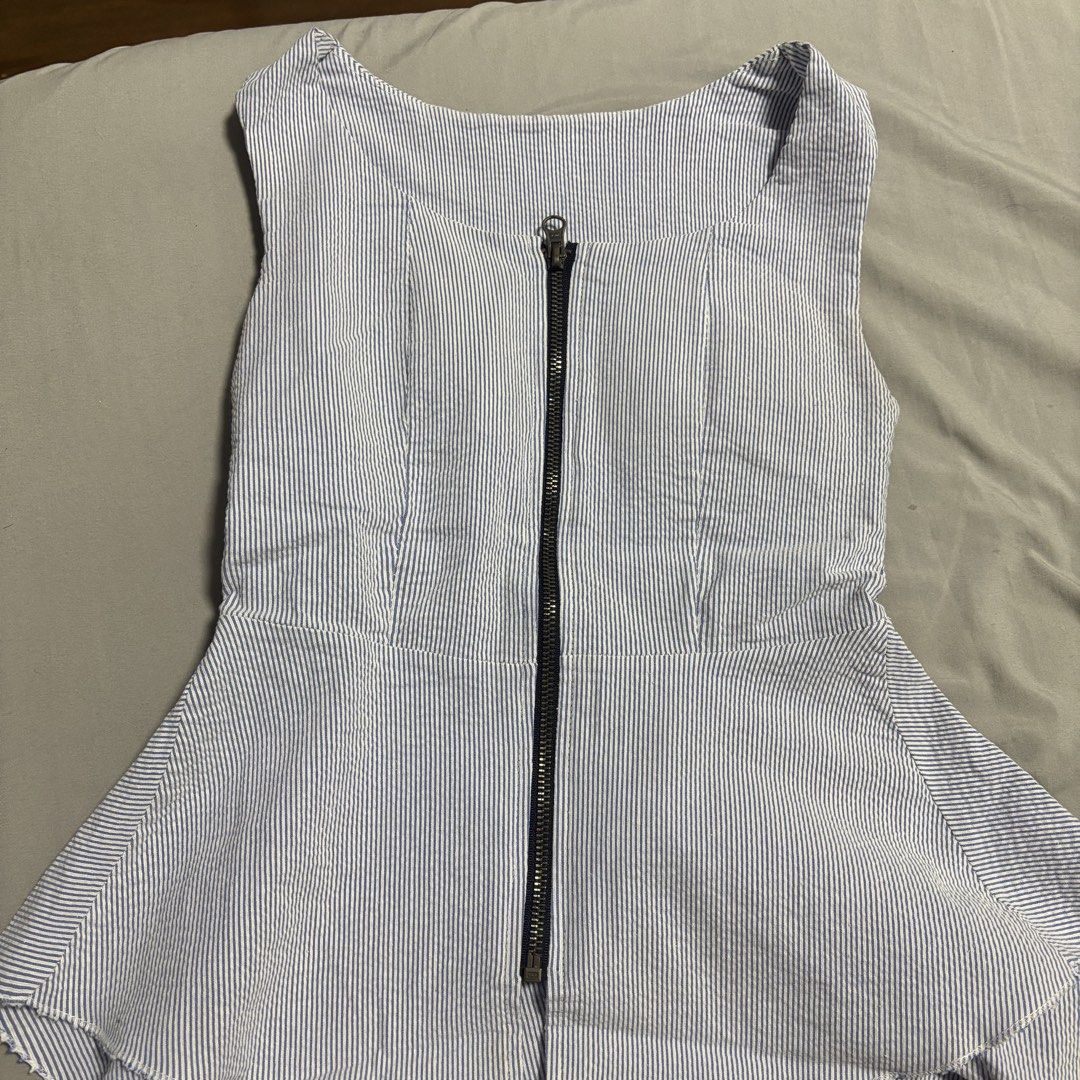 Blue and White Striped Top with Zipper (Category: Blouses) located in Manila. Submitted by mleia (Listing ID 1428351913, Image 1). Description: Sleeveless top features a blue and white striped pattern. It has a full-length zipper down the front. The top has a peplum-style hem. It is a stylish piece that can be dressed up or down. Padded..