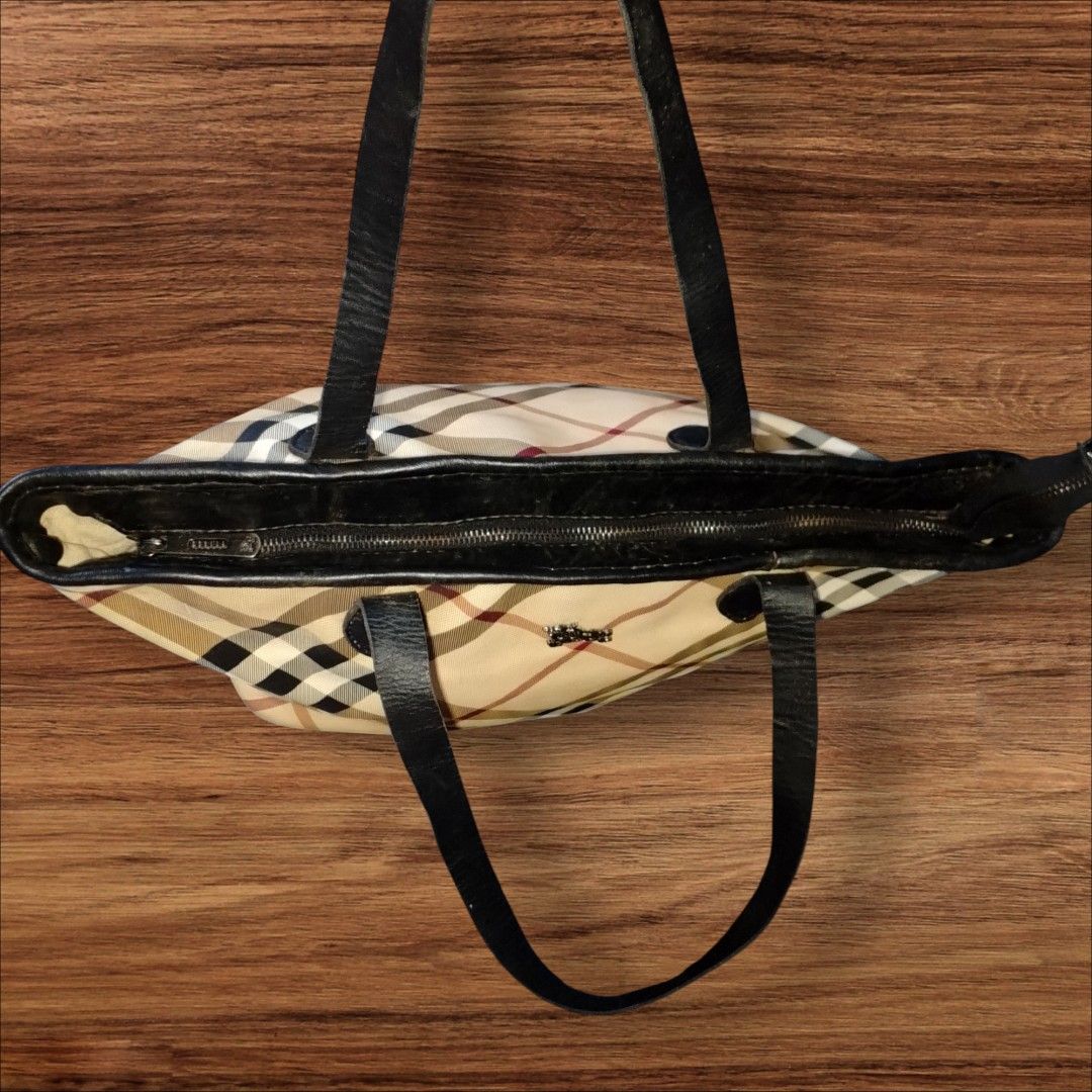 Burberry Nova CheckTote Bag (Category: Luxury Bags & Wallets) located in Cebu City. Submitted by jc_online_shop (Listing ID 1428282300, Image 3). Description: Burberry tote bag features the iconic checkered pattern. It has black leather handles and trim. The bag has a rectangular shape with a zipper closure. A small Burberry logo is visible on the front. can fit laptop up to 15 inches 18" x 12" x 7" zip closure.