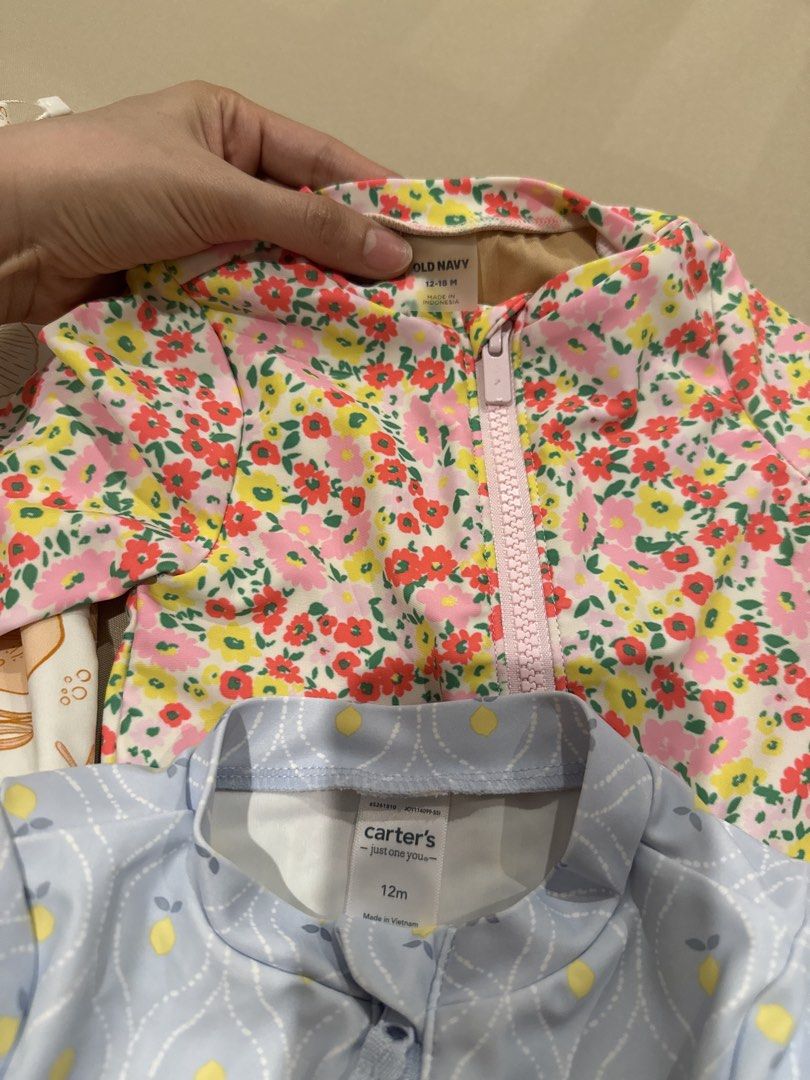 Carter's, Old Navy, Little Lass Swimsuit Bundle (Category: Babies & Kids Fashion) located in Manila. Submitted by apc.declutter (Listing ID 1428351332, Image 3). Description: Bundle of four long-sleeved swimsuits for babies and toddlers. Includes a light blue Carter's swimsuit with lemon pattern, a floral Old Navy swimsuit, a Little Lass unicorn swimsuit, and a seashell-patterned Little Lass swimsuit. All have a zipper closure and are designed fo