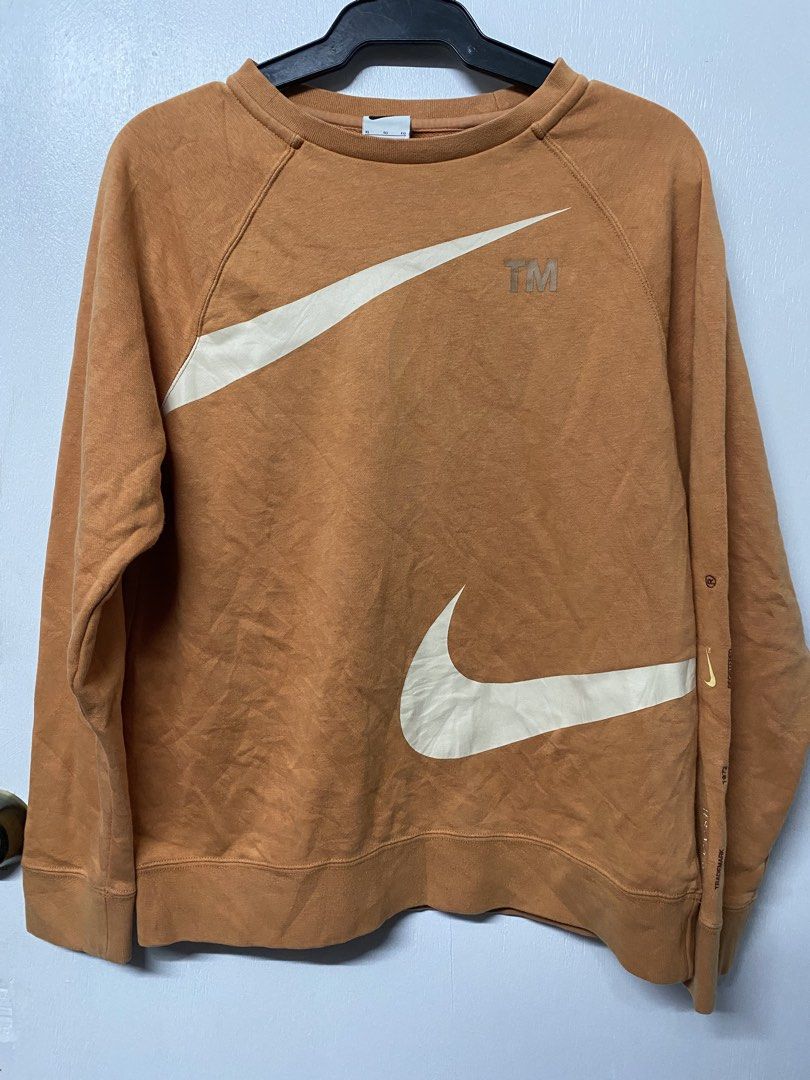 Nike Big Swoosh Sweatshirt XL (Category: Coats, Jackets and Outerwear) located in Quezon City. Submitted by thriftkitaph (Listing ID 1428397238, Image 1). Description: Nike sweatshirt in a burnt orange color with a large white swoosh design. Features the Nike logo on the tag and the word "registered" and "trademark" printed on the sleeve. The size is XL. Made in China..