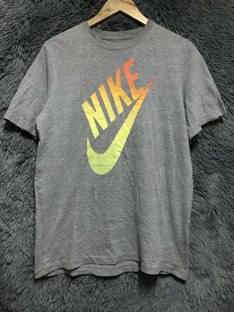 Nike T-shirt XL (Category: Tshirts & Polo Shirts ) located in Manila. Submitted by thrift_marvs (Listing ID 1428417585, Image 1). Description: Gray Nike T-shirt with a large Nike logo in a gradient of yellow, orange, and red. The shirt is size XL. Made in El Salvador. The shirt has a crew neck and short sleeves..