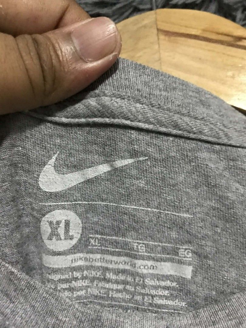 Nike T-shirt XL (Category: Tshirts & Polo Shirts ) located in Manila. Submitted by thrift_marvs (Listing ID 1428417585, Image 3). Description: Gray Nike T-shirt with a large Nike logo in a gradient of yellow, orange, and red. The shirt is size XL. Made in El Salvador. The shirt has a crew neck and short sleeves..