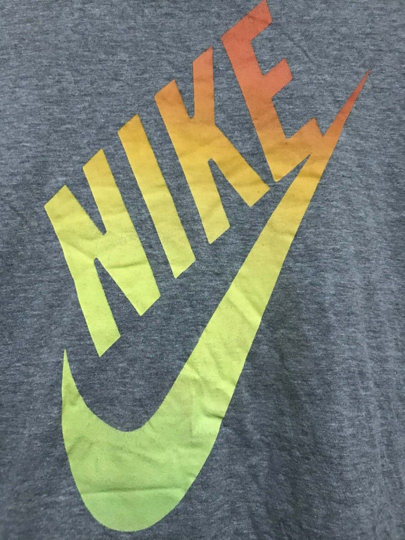 Nike T-shirt XL (Category: Tshirts & Polo Shirts ) located in Manila. Submitted by thrift_marvs (Listing ID 1428417585, Image 2). Description: Gray Nike T-shirt with a large Nike logo in a gradient of yellow, orange, and red. The shirt is size XL. Made in El Salvador. The shirt has a crew neck and short sleeves..