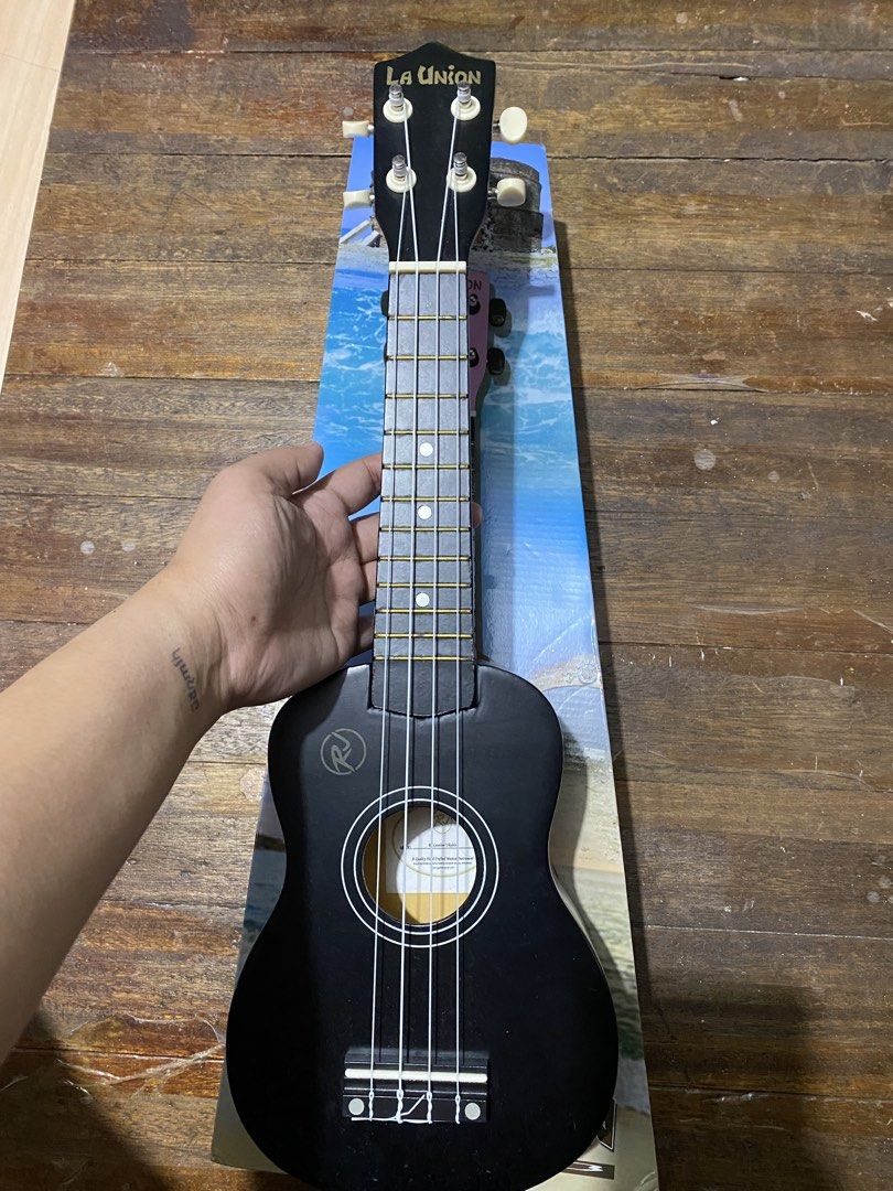 RJ La Union Ukulele Soprano with Bag (Category: Musical Instruments) located in Makati City. Submitted by lasthing.22 (Listing ID 1428423288, Image 2). Description: La Union ukulele comes with a black finish and a matching carrying case. The ukulele features a black headstock with the brand name in gold lettering. The body has a round sound hole and white accents. The included case has a zipper closure and the RV logo. RFS: Declutter With origina