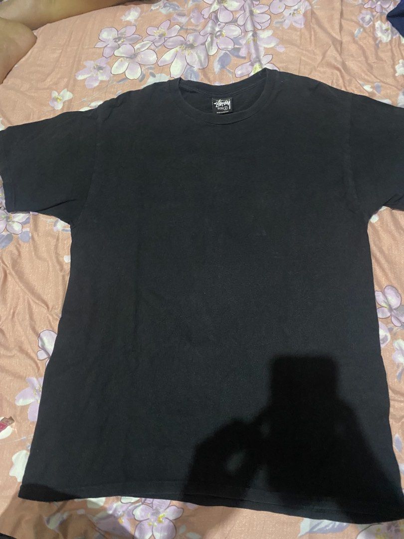 Stussy 8 Ball Graphic Tee (Category: Tshirts & Polo Shirts ) located in Batangas. Submitted by aidenbotchog (Listing ID 1428303188, Image 2). Description: Black Stussy t-shirt featuring the iconic 8 ball graphic on the back. The shirt has a crew neck and short sleeves. The tag indicates it is made of 100% cotton. The size is M. The shirt has the Stussy logo on the front. L29 W19.