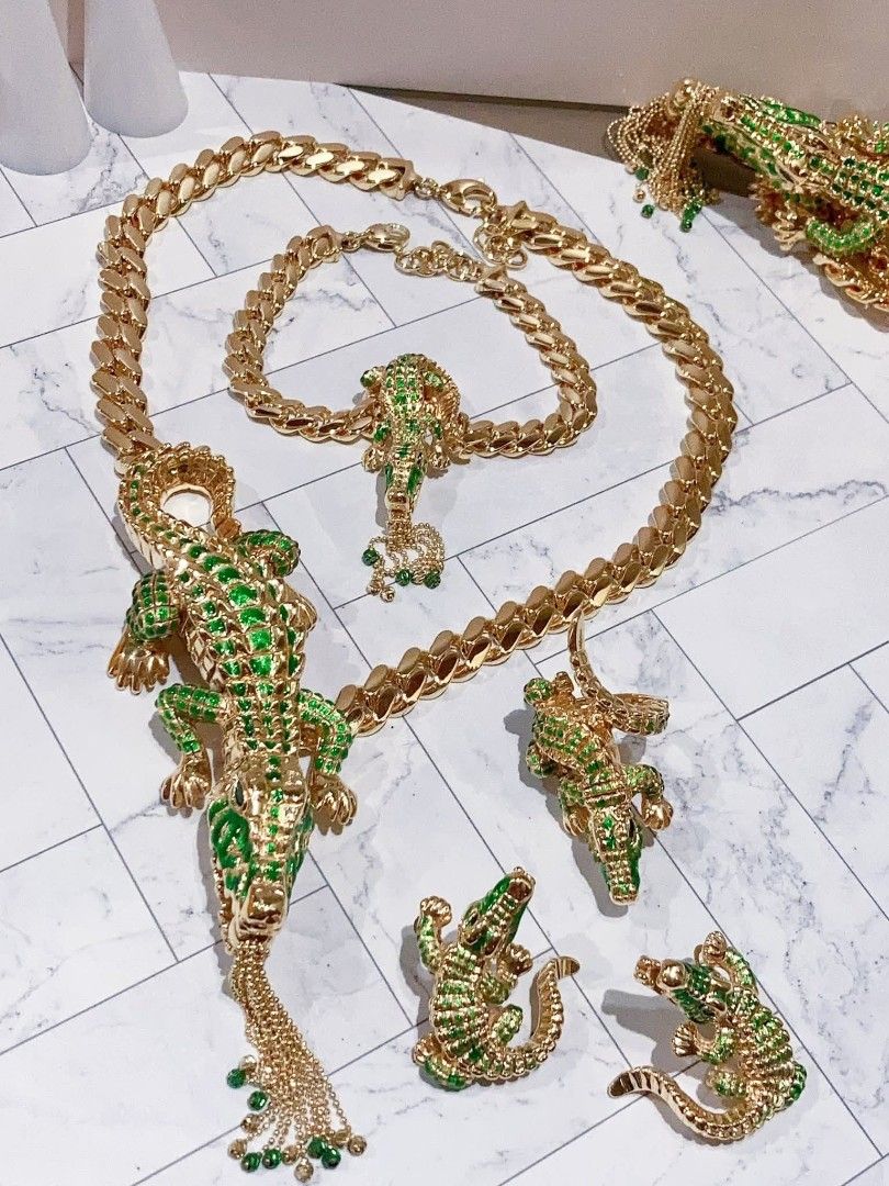 18k Gold Alligator Jewelry Set (Category: Earrings) located in Manila. Submitted by primejewelry (Listing ID 1428476539, Image 2). Description: Elegant gold-toned jewelry set featuring alligator designs. Includes a necklace, bracelet, and earrings. The necklace has a large alligator pendant with green enamel detailing. The bracelet also features an alligator design. The earrings have a smaller alligator design. A unique and eye-catching set perfe