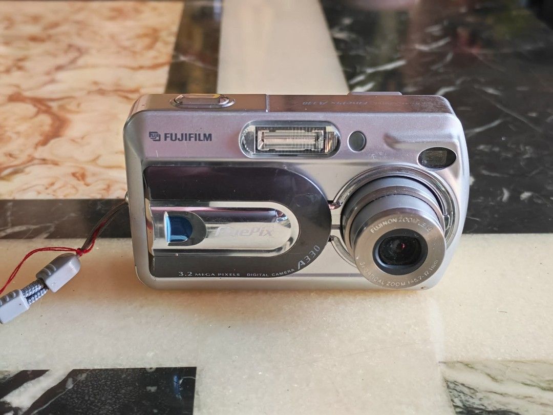 Fujifilm FinePix A330 Digital Camera (Category: Cameras) located in Manila. Submitted by jonrick.co (Listing ID 1428514334, Image 1). Description: Fujifilm FinePix A330 digital camera. It has a 3.2 megapixel resolution. The camera is silver and has a built-in flash. It includes a lens and a power cable. The camera's model name is visible on the top of the camera. execellent working condition slight issue pag oudoor minsan over exposed 16mb xd car