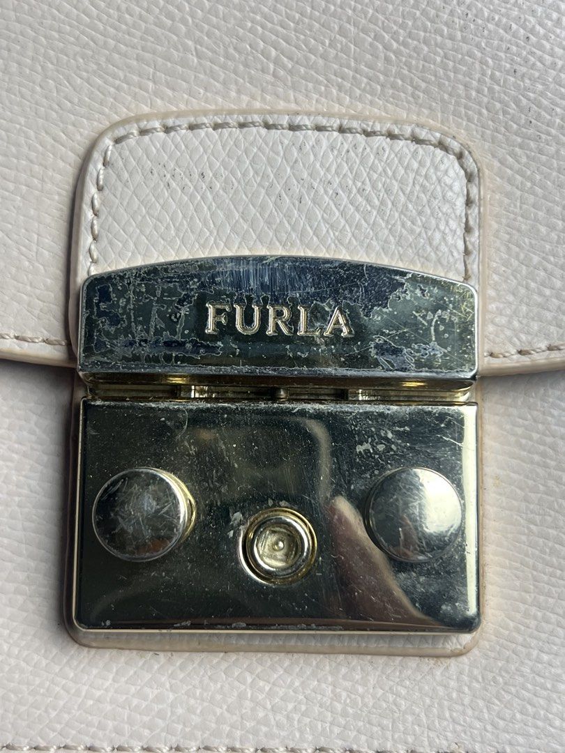 Furla Mini Crossbody Bag (Category: Luxury Bags & Wallets) located in Manila. Submitted by reclaim.13 (Listing ID 1428490751, Image 3). Description: - IN GREAT CONDITION - FOR WOMENS - VERY UNIQUE STYLE - ISSUE IS INDICATE ON THE PICTURES SLIDE Furla mini crossbody bag features a light pink exterior with a chain strap. It has a flap closure with the Furla logo. The interior has a small pocket. The bag is marked "Made in Italy". Includes a small l