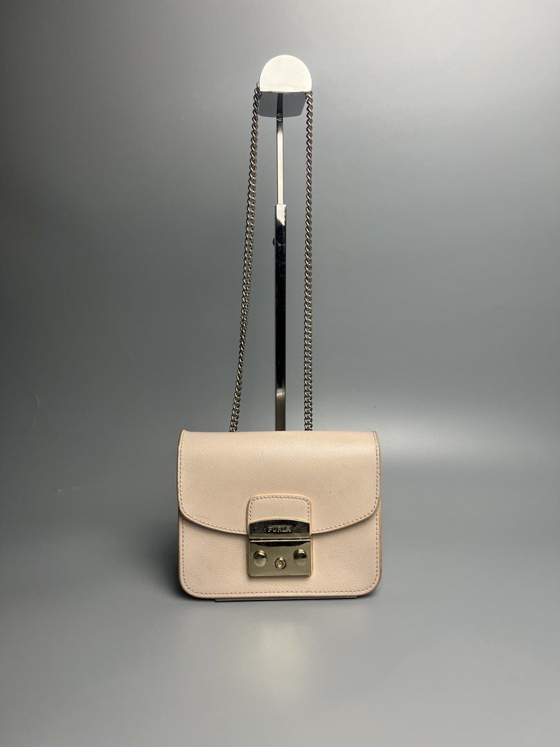 Furla Mini Crossbody Bag (Category: Luxury Bags & Wallets) located in Manila. Submitted by reclaim.13 (Listing ID 1428490751, Image 1). Description: - IN GREAT CONDITION - FOR WOMENS - VERY UNIQUE STYLE - ISSUE IS INDICATE ON THE PICTURES SLIDE Furla mini crossbody bag features a light pink exterior with a chain strap. It has a flap closure with the Furla logo. The interior has a small pocket. The bag is marked "Made in Italy". Includes a small l