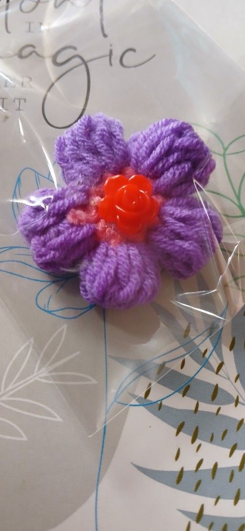 Handmade Crochet Flower Embellishment (Category: Hair Accessories) located in Cavite. Submitted by decluttermum_ (Listing ID 1428460795, Image 1). Description: Handmade crochet flower embellishment. It features purple yarn petals and a bright orange center. The flower is packaged in clear plastic. It would be perfect for adding a unique touch to your crafts, clothing, or accessories. It is a charming and eye-catching detail. .
