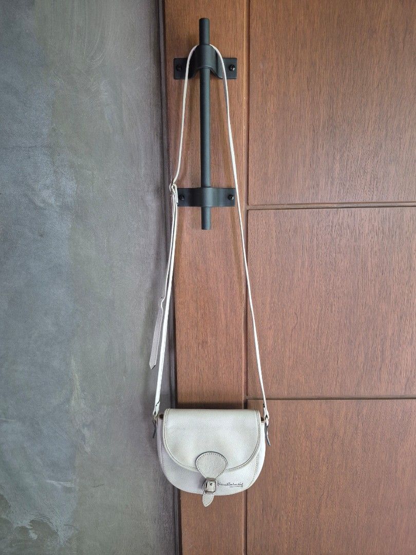 Pierre Balmain Crossbody Bag (Category: Luxury Bags & Wallets) located in Cainta. Submitted by Gp0ps (Listing ID 1428440889, Image 2). Description: Pierre Balmain crossbody bag features a flap closure with a buckle. It has a long strap for shoulder or crossbody wear. The bag is a light color, possibly off-white or cream. The bag has a curved shape..