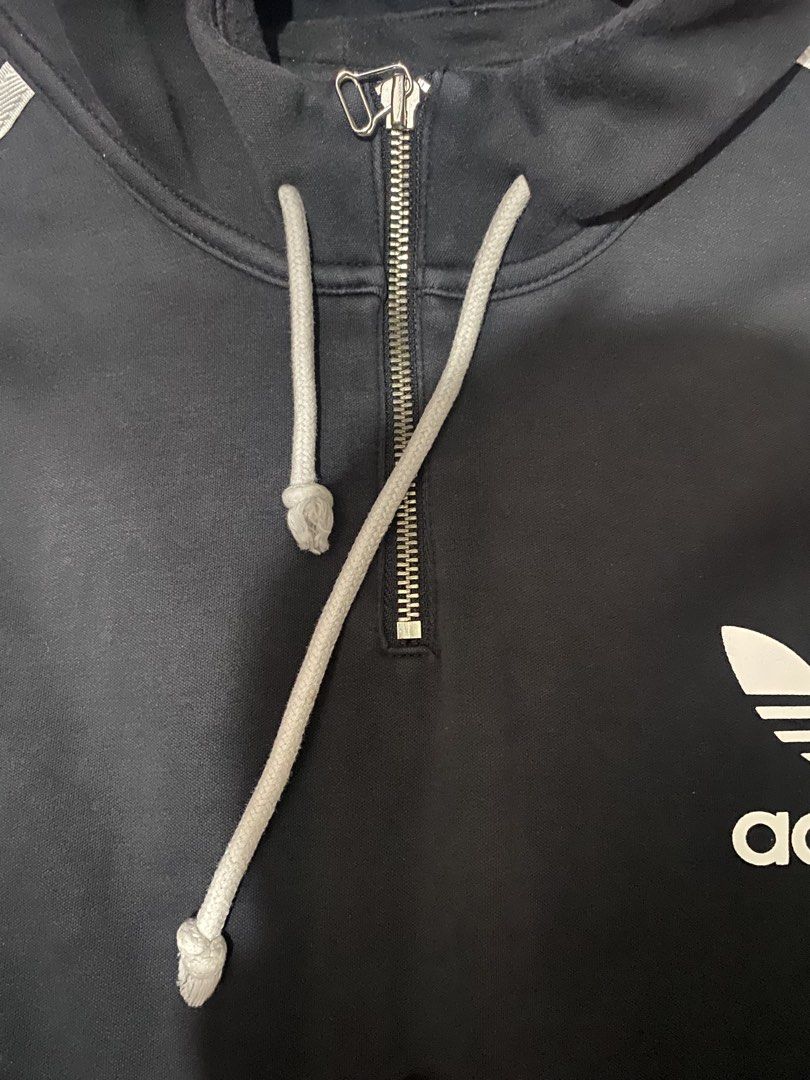 Adidas Terry Hooded Sweatshirt (Category: Coats, Jackets and Outerwear) located in Batangas. Submitted by aidenbotchog (Listing ID 1428626904, Image 3). Description: Black Adidas hoodie with white stripes on the sleeves and a front pocket. Features a half-zip closure and the Adidas logo on the chest. The tag indicates the size is L. Made with a blend of cotton and polyester. The hoodie has a hood with drawstrings L28W23.