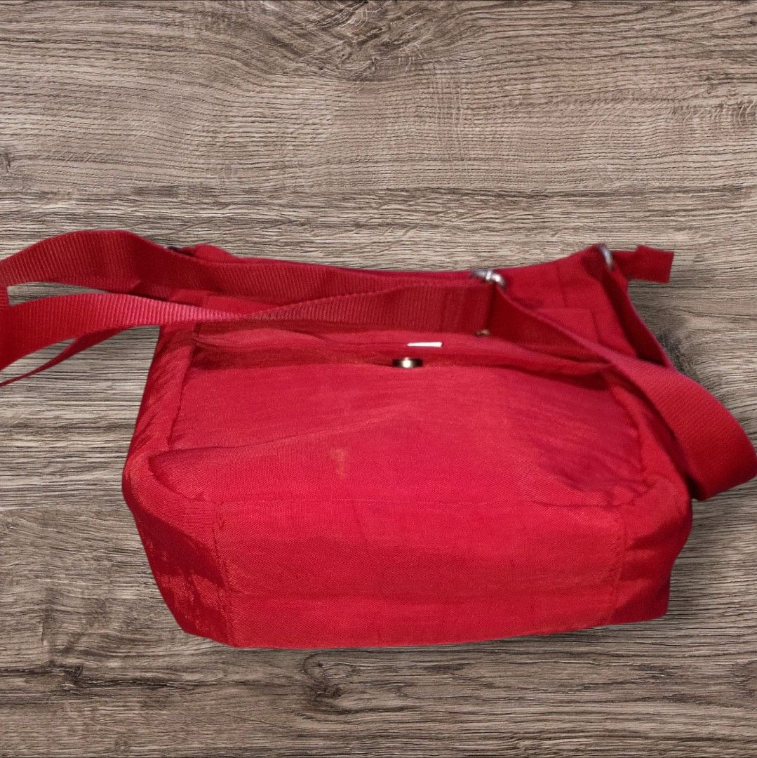 Auth Baggallini Red Nylon Crossbody Bag (Category: Cross-body Bags) located in Cebu City. Submitted by jc_online_shop (Listing ID 1428613962, Image 3). Description: Red Baggallini crossbody bag features a main compartment with a zipper closure and multiple interior pockets. It has an adjustable shoulder strap and an exterior pocket with a magnetic snap closure. The bag's interior is lined with a gray fabric. The bag has a small stain on the front