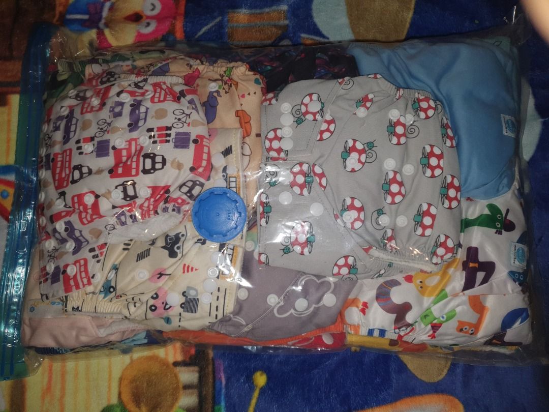 Cloth Diaper Set (Category: Diapers & Baby Wipes) located in Quezon City. Submitted by hh.tt (Listing ID 1428753855, Image 2). Description: Set includes several cloth diapers and inserts. The diapers feature various colorful patterns, including cars, mushrooms, and other designs. The set also includes a green diaper with snaps. The inserts are white and appear to be absorbent. 24pcs Next9 cloth diapers (assorted designs) 5 or 6pcs Eco nappies 12p
