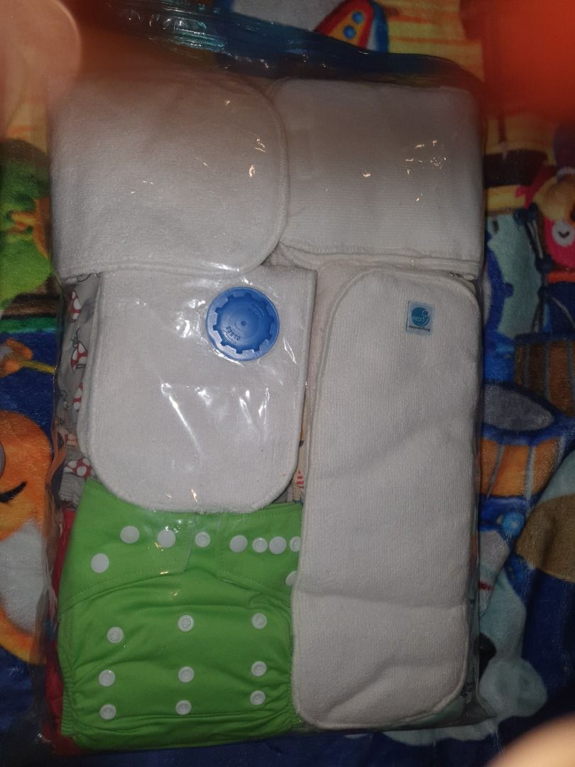 Cloth Diaper Set (Category: Diapers & Baby Wipes) located in Quezon City. Submitted by hh.tt (Listing ID 1428753855, Image 3). Description: Set includes several cloth diapers and inserts. The diapers feature various colorful patterns, including cars, mushrooms, and other designs. The set also includes a green diaper with snaps. The inserts are white and appear to be absorbent. 24pcs Next9 cloth diapers (assorted designs) 5 or 6pcs Eco nappies 12p