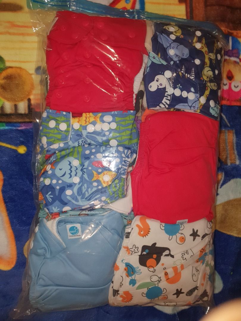 Cloth Diaper Set (Category: Diapers & Baby Wipes) located in Quezon City. Submitted by hh.tt (Listing ID 1428753855, Image 1). Description: Set includes several cloth diapers and inserts. The diapers feature various colorful patterns, including cars, mushrooms, and other designs. The set also includes a green diaper with snaps. The inserts are white and appear to be absorbent. 24pcs Next9 cloth diapers (assorted designs) 5 or 6pcs Eco nappies 12p