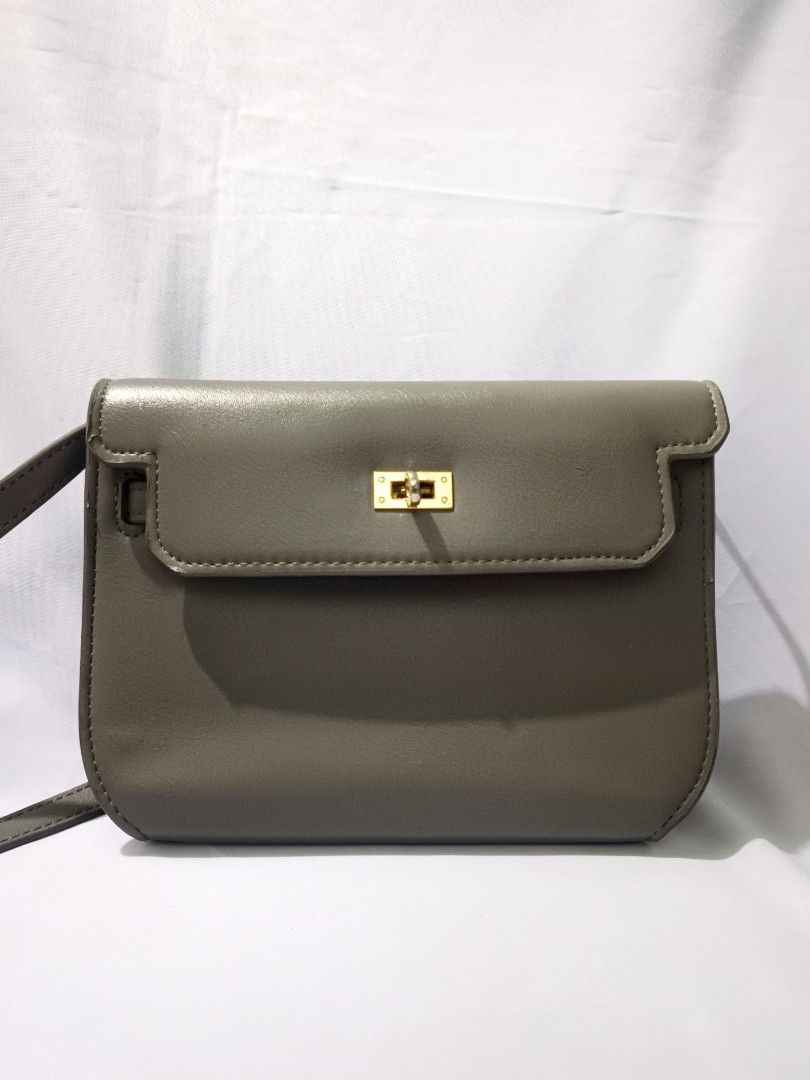 Grey Crossbody Bag with Gold Hardware (Category: Luxury Bags & Wallets) located in Bacoor. Submitted by nia.niya015 (Listing ID 1428736448, Image 1). Description: Strap length - 22 inches Depth - 3 inches Width - 9.5inches Height - 7 inches -has flaws but barely noticeable -gold hardware is slightly fading -may bakbak sa straps Grey crossbody bag features a rectangular shape with a flap closure and gold-colored hardware. The bag has a long, adjus