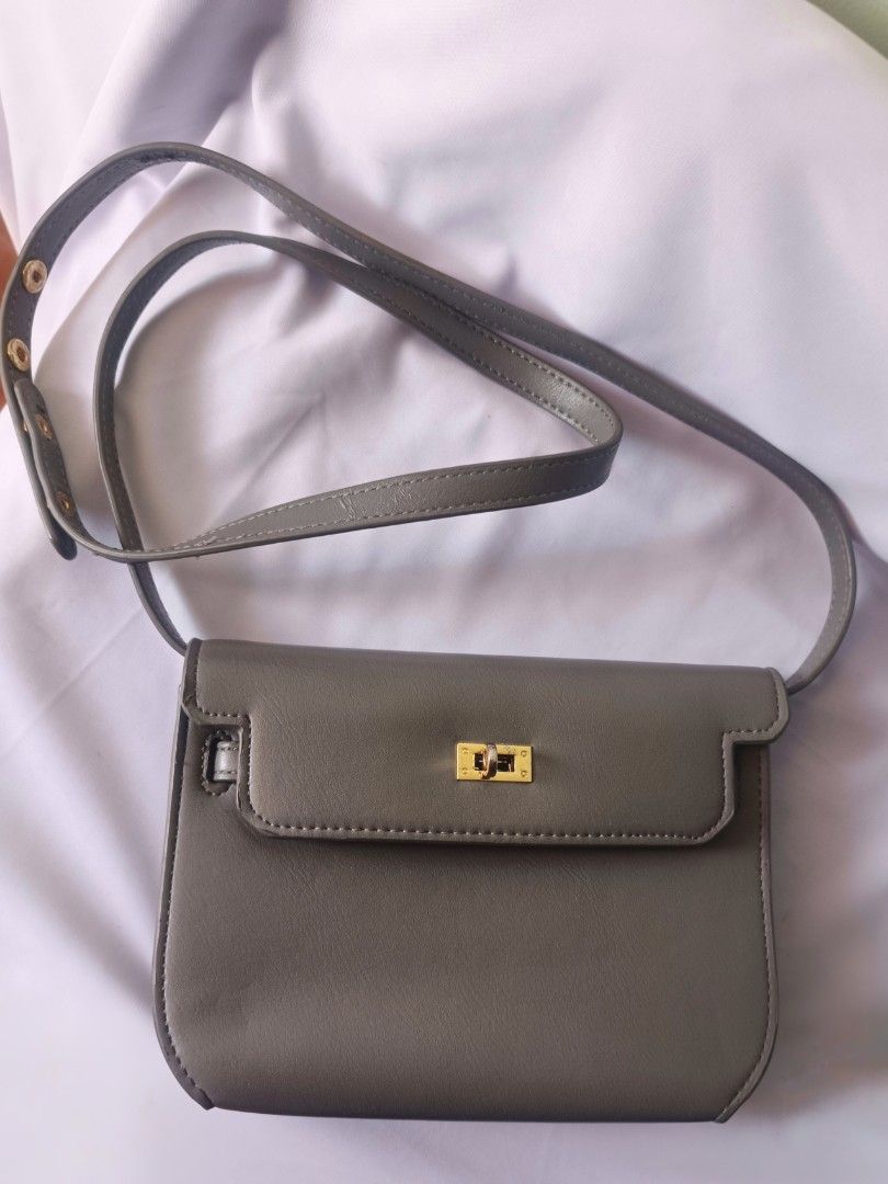 Grey Crossbody Bag with Gold Hardware (Category: Luxury Bags & Wallets) located in Bacoor. Submitted by nia.niya015 (Listing ID 1428736448, Image 2). Description: Strap length - 22 inches Depth - 3 inches Width - 9.5inches Height - 7 inches -has flaws but barely noticeable -gold hardware is slightly fading -may bakbak sa straps Grey crossbody bag features a rectangular shape with a flap closure and gold-colored hardware. The bag has a long, adjus