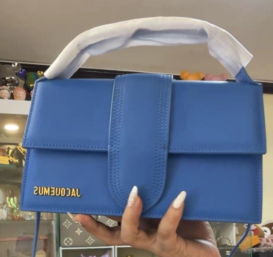 Jacquemus Le Bambino Bag - Blue (Category: Luxury Bags & Wallets) located in Manila. Submitted by bellissima05 (Listing ID 1428731042, Image 1). Description: Vibrant blue Jacquemus Le Bambino handbag. Features a structured rectangular shape with a flap closure and a top handle. The bag has a prominent front flap with a stitched detail and the brand's logo in gold lettering. Includes a detachable shoulder strap. Product information Brand: Jacquemu