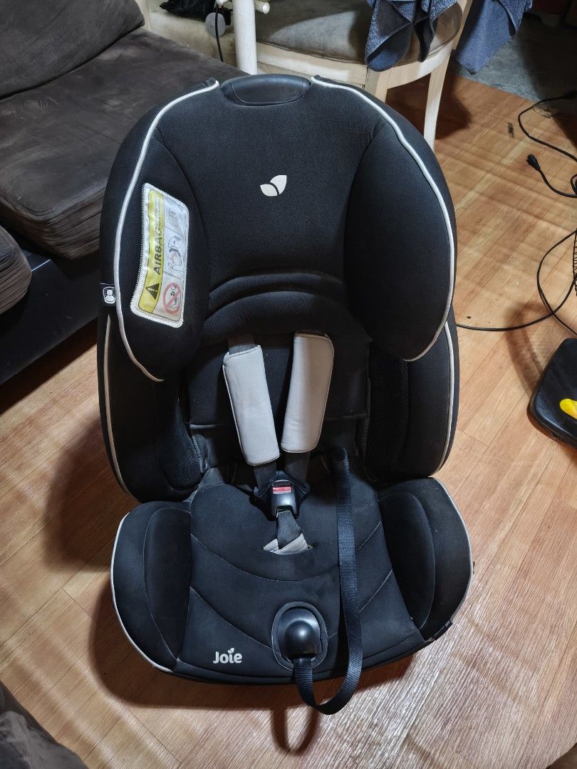 Joie Car Seat (Category: Car Seats) located in Paranaque City. Submitted by judy.arquillos (Listing ID 1428651509, Image 1). Description: Black Joie car seat. Features include a headrest, shoulder pads, and a five-point harness. The seat has side impact protection and is suitable for children from 0-18kg. The seat has a red adjustment lever and a label indicating the correct installation. The seat has a Joie logo. 2000+SHIP J&T LALAMOVE PICK-UP.