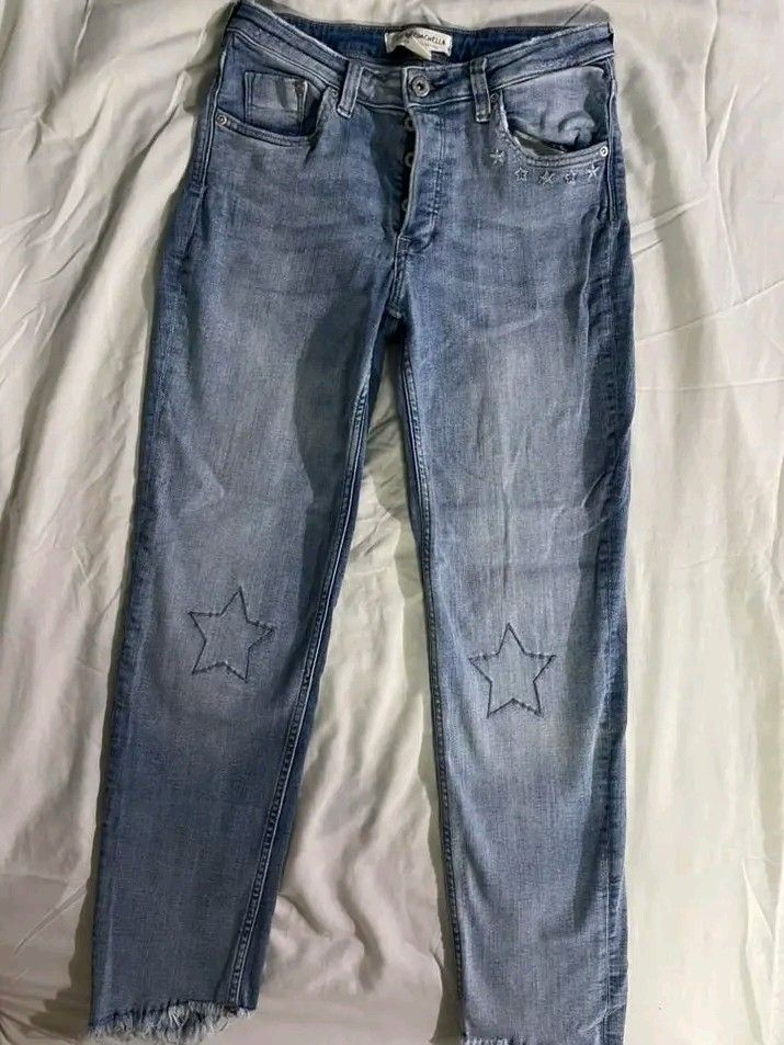H&M x Coachella Light Wash Star Patch Jeans (Category: Jeans) located in Taytay. Submitted by calige4n (Listing ID 1428774291, Image 1). Description: Light wash denim jeans with star patches on the knees. Features a button closure and pockets. The jeans have a raw hem. The jeans have a classic five-pocket design..