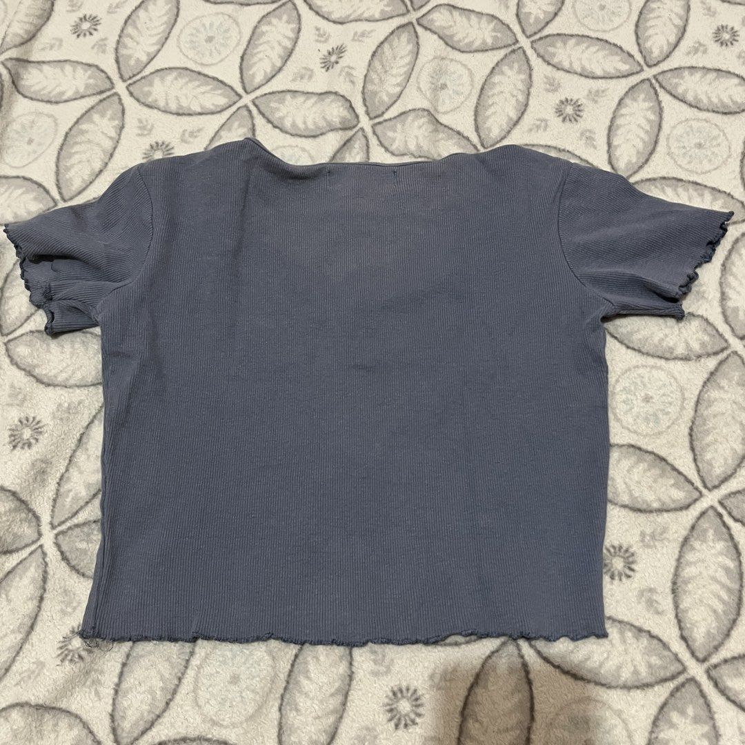 Pull&Bear V-neck Crop Top (Category: Sleeveless) located in Rodriguez. Submitted by decluttrey (Listing ID 1428759998, Image 2). Description: Features a V-neck design and short sleeves. Has a ribbed texture and a wavy hemline. The top is a muted blue-grey color. There is a small stain on the front of the top, but it should come off after washing. Size Large (L) but can fit XS to M Still nego.